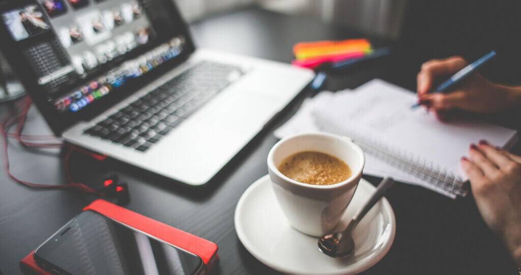 Woman working at a table with a laptop and coffee